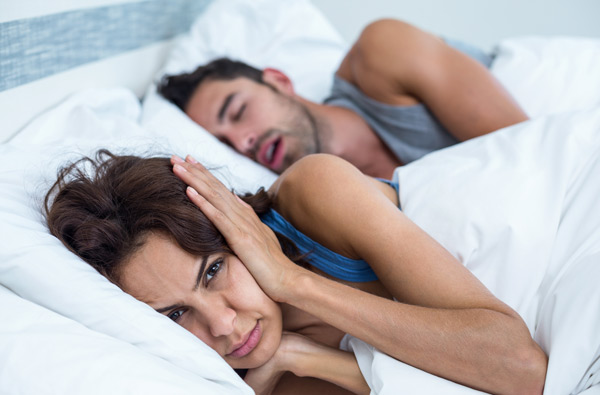 Woman covering ears while husband snores in Cincinnati needs a sleep apnea assessment from Sleep Apnea Solutions of Cincinnati in Cincinnati, OH