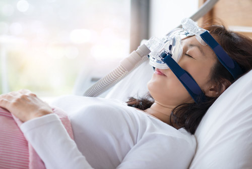 Woman sleeping with help from a CPAP machine after visit to Sleep Apnea Solutions of Cincinnati in Cincinnati, OH